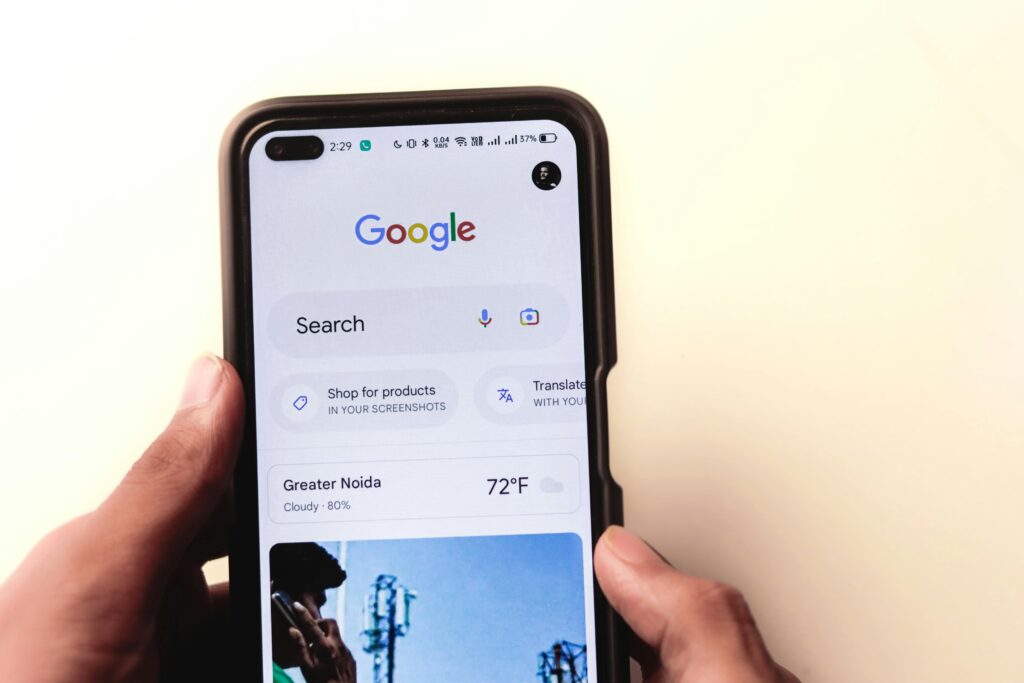 Google Business Listing Optimization A close-up of a hand holding a smartphone with Google search displayed on the screen.